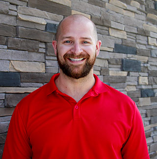 Matthew Reis, a young man in a red polo shirt, standing in front of a brick wall